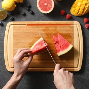 Watermelon being cut on a bamboo board with a visible perimeter groove